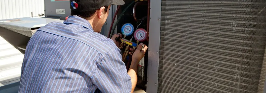 HVAC technician servicing a condenser unit in West Bridgewater